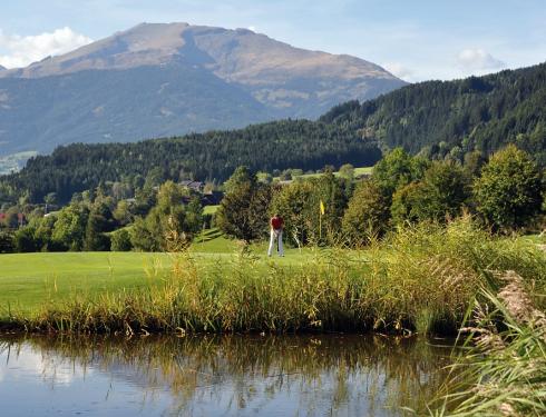 Golfanlage mit Teich im Vordergrund und Bergen im Hintergrund Golfanlage Millstaetter See