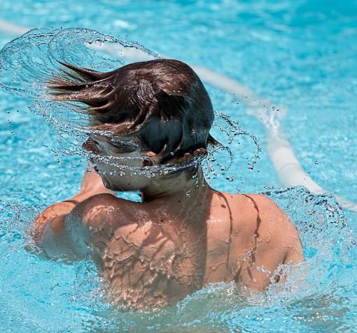 Junge im Schwimmbad taucht aus Wasser auf Schwimmspaß
